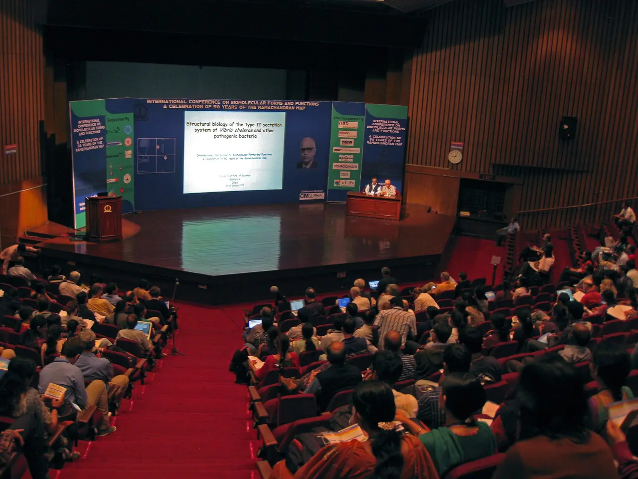 A full auditorium at an international congress, with the speakers on stage.